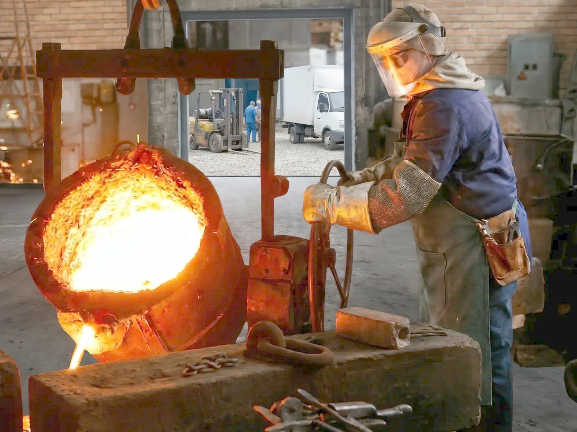 Foundry worker pouring molten bronze into a mold